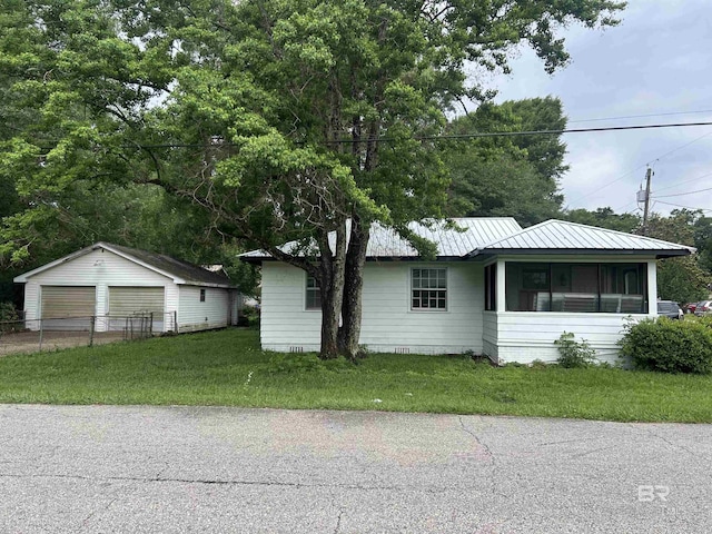view of front of home with a detached garage, an outdoor structure, a front lawn, crawl space, and metal roof