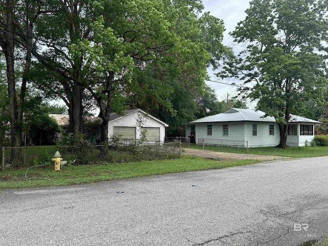 view of front of home featuring fence, a detached garage, and an outdoor structure