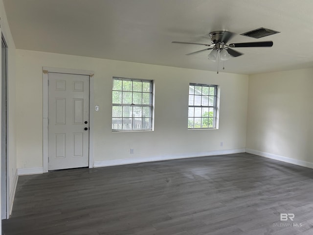 empty room with dark wood finished floors, a ceiling fan, and baseboards