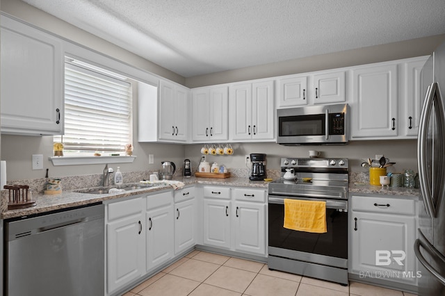 129 Oakwood Ave, Fairhope, AL 36532 - kitchen with stainless steel appliances, a sink, white cabinetry, a textured ceiling, and light tile patterned flooring