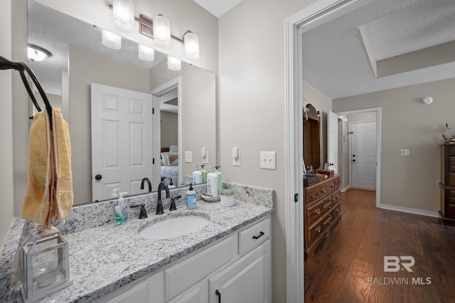 129 Oakwood Ave, Fairhope, AL 36532 - bathroom with connected bathroom, vanity, wood finished floors, a textured ceiling, and baseboards