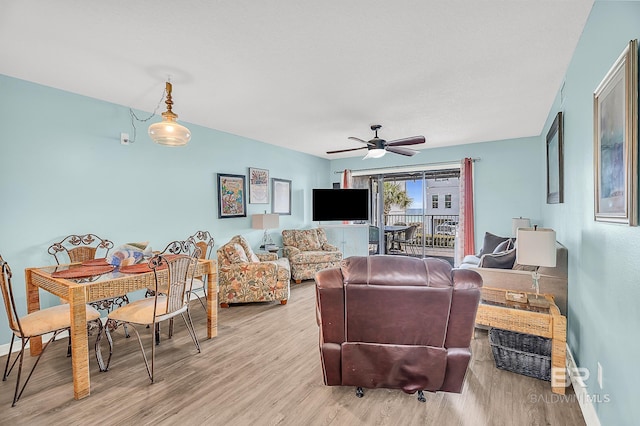 living room featuring light wood-type flooring, a ceiling fan, and baseboards