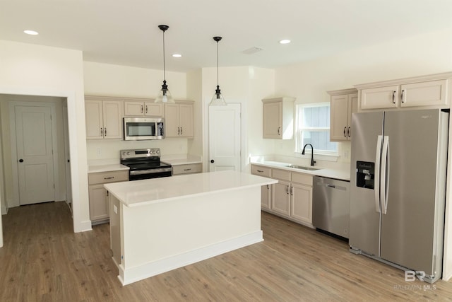 kitchen with stainless steel appliances, sink, light hardwood / wood-style flooring, a center island, and hanging light fixtures