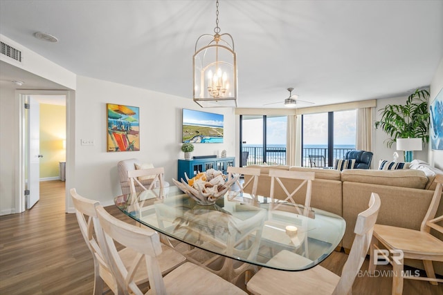 dining room with visible vents, baseboards, wood finished floors, and ceiling fan with notable chandelier