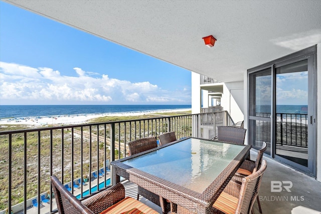 balcony with outdoor dining space, a beach view, and a water view