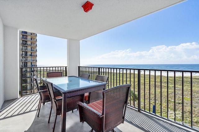 balcony featuring outdoor dining area and a water view