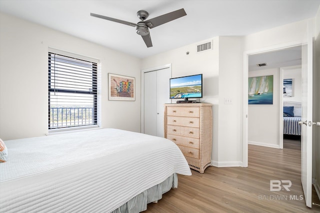 bedroom featuring wood finished floors, visible vents, a closet, and baseboards