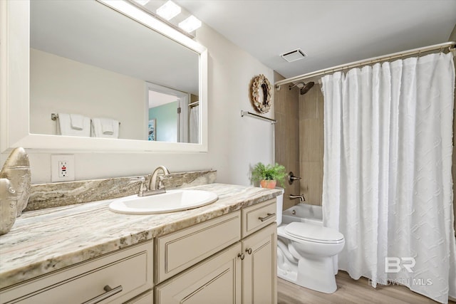 full bath with visible vents, shower / bath combo with shower curtain, toilet, wood finished floors, and vanity