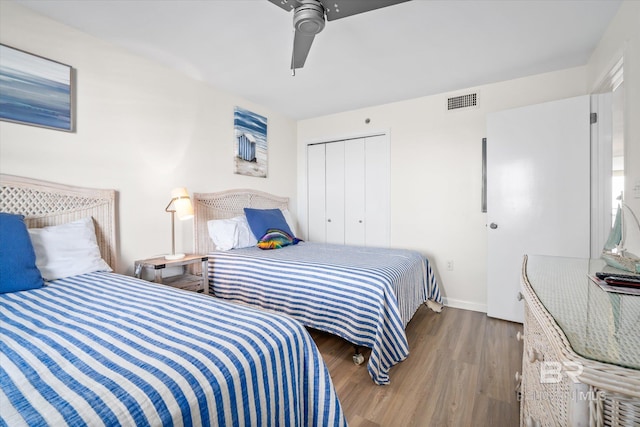 bedroom with visible vents, baseboards, ceiling fan, wood finished floors, and a closet