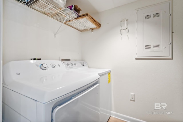 laundry room featuring electric panel, baseboards, washing machine and dryer, and laundry area