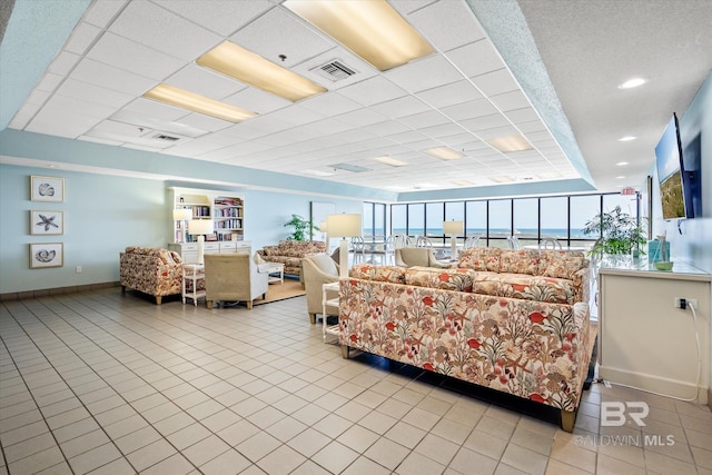 tiled living room with visible vents, baseboards, and a drop ceiling