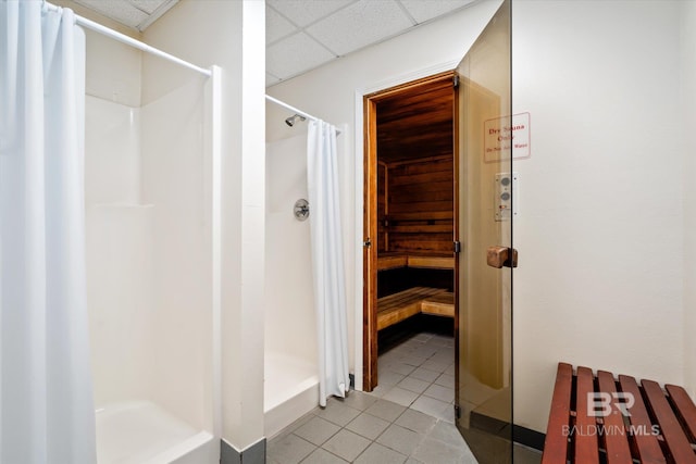 full bathroom with tile patterned flooring, a sauna, a stall shower, and a paneled ceiling