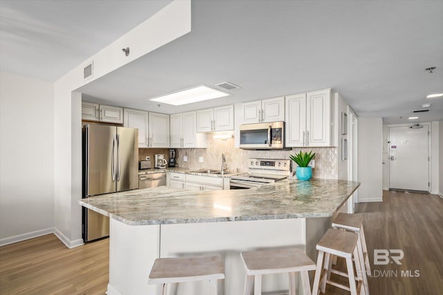 kitchen with a sink, tasteful backsplash, appliances with stainless steel finishes, and a peninsula