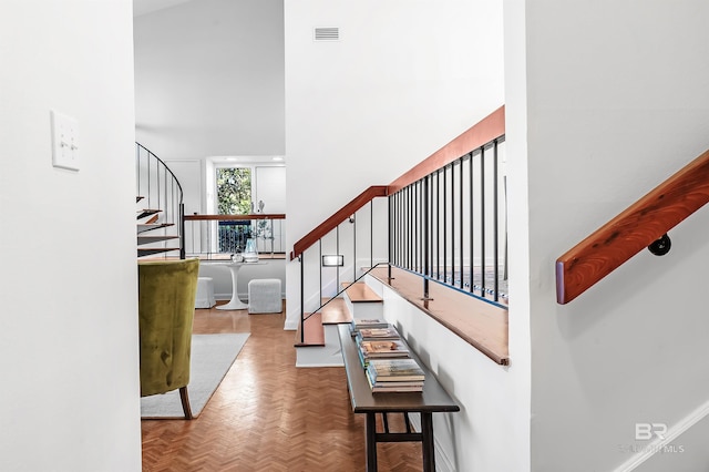 staircase featuring a towering ceiling and visible vents