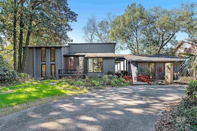 mid-century inspired home with aphalt driveway and a front lawn