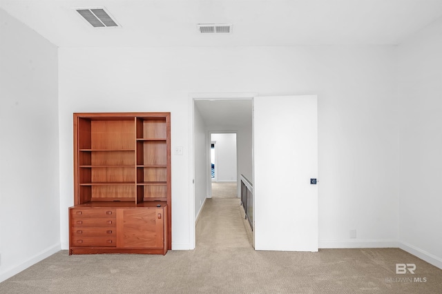 interior space featuring visible vents, light carpet, and baseboards