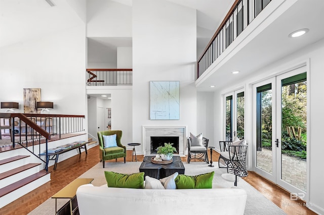 living room with stairs, french doors, a fireplace, and a high ceiling