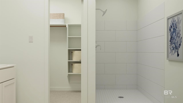 bathroom featuring a shower stall, a spacious closet, and vanity