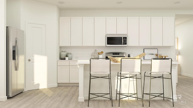 kitchen featuring light countertops, light wood-type flooring, stainless steel appliances, and tasteful backsplash