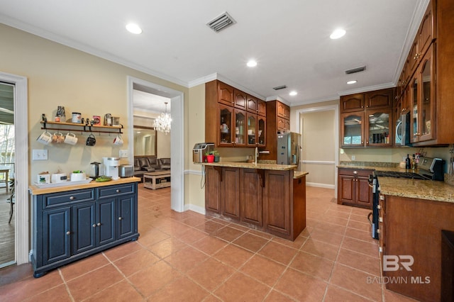 kitchen with light tile patterned floors, kitchen peninsula, stainless steel appliances, crown molding, and an inviting chandelier