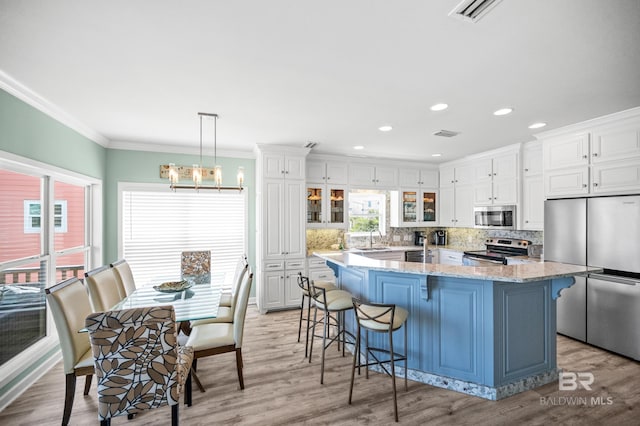 kitchen featuring visible vents, a breakfast bar, ornamental molding, stainless steel appliances, and a sink