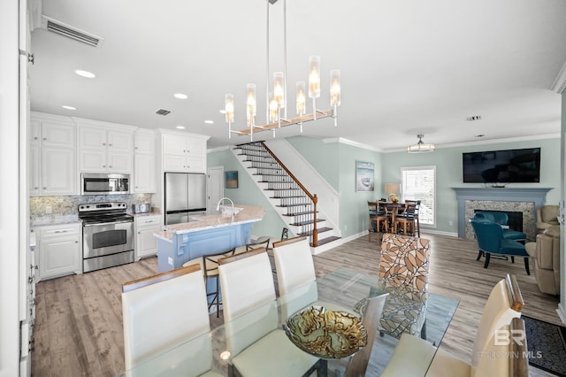 dining room with visible vents, a fireplace, stairs, and crown molding