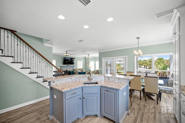 kitchen with an inviting chandelier, ornamental molding, a fireplace, and light wood finished floors