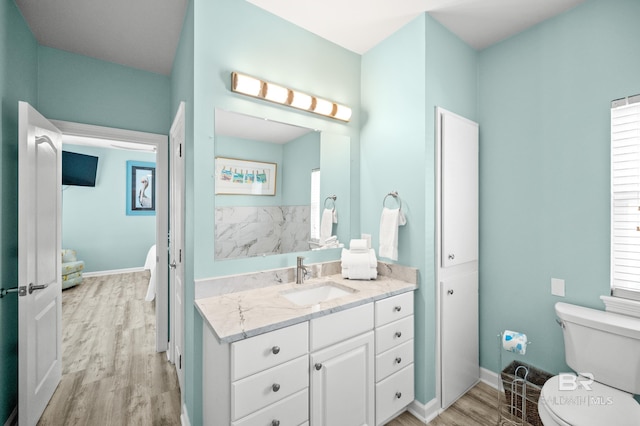 bathroom featuring toilet, vanity, baseboards, and wood finished floors