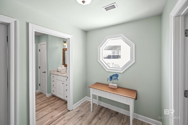 corridor featuring light wood-style flooring, baseboards, and visible vents