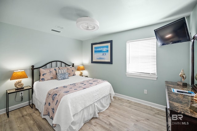 bedroom with light wood finished floors, visible vents, and baseboards