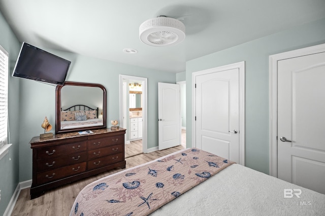 bedroom featuring light wood-type flooring, multiple windows, baseboards, and ensuite bathroom