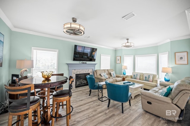 living area featuring light wood-style flooring, a healthy amount of sunlight, and a glass covered fireplace