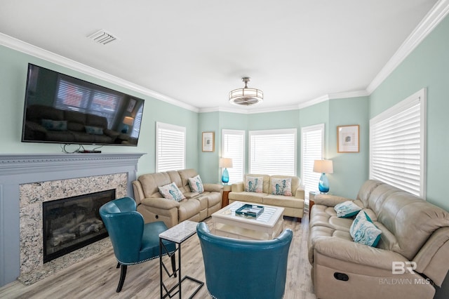 living room with visible vents, wood finished floors, a high end fireplace, and crown molding