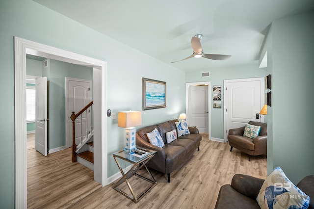 living room featuring visible vents, light wood-type flooring, stairs, and baseboards