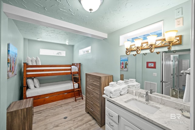 bathroom with visible vents, a textured ceiling, vanity, and wood finished floors