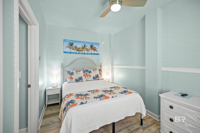 bedroom with light wood-style flooring, a ceiling fan, and baseboards