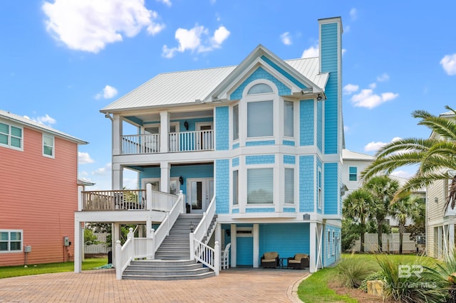 view of front of property featuring stairway, a chimney, metal roof, decorative driveway, and a standing seam roof