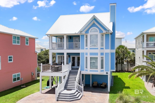 back of property featuring stairway, decorative driveway, french doors, and a lawn