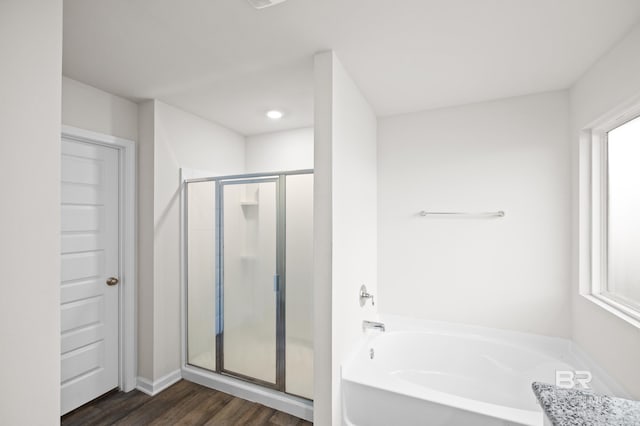 bathroom featuring plus walk in shower and wood-type flooring