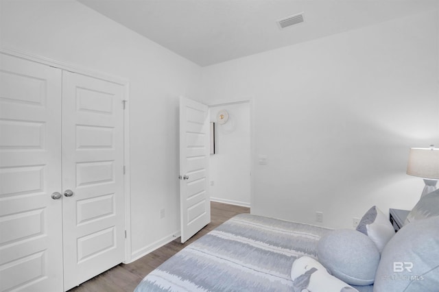 bedroom with dark hardwood / wood-style floors and a closet