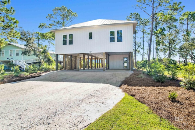 beach home with metal roof, dirt driveway, stairs, and a carport
