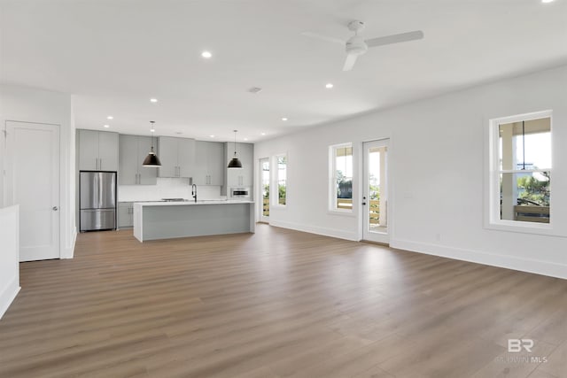 unfurnished living room featuring ceiling fan, baseboards, wood finished floors, and recessed lighting
