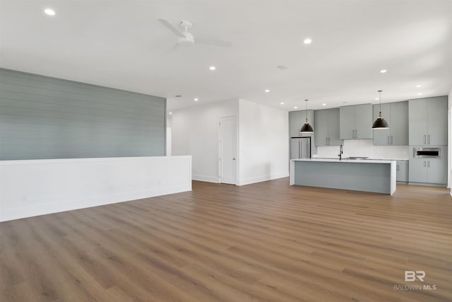 unfurnished living room featuring light wood finished floors, a sink, baseboards, recessed lighting, and ceiling fan