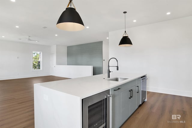 kitchen featuring dark wood finished floors, beverage cooler, an island with sink, and a sink