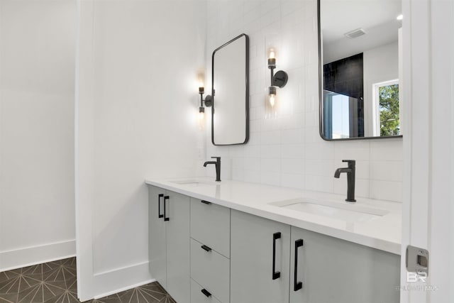 bathroom with decorative backsplash, a sink, visible vents, and double vanity