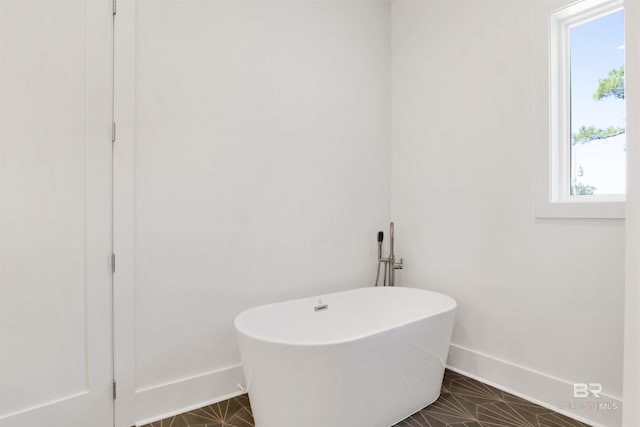 full bathroom featuring baseboards and a freestanding tub
