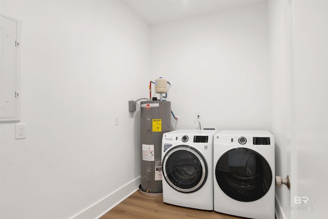 clothes washing area featuring light wood-style floors, water heater, washing machine and dryer, baseboards, and laundry area