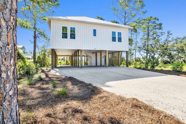 coastal home with a carport, driveway, board and batten siding, and metal roof