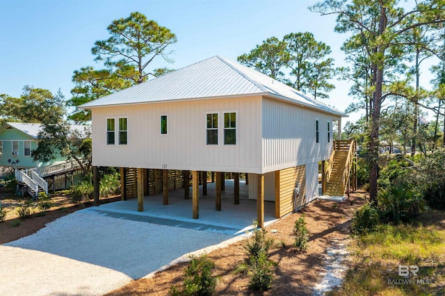view of front of property with a carport, stairs, and dirt driveway