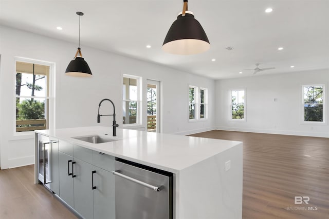 kitchen with a kitchen island with sink, stainless steel dishwasher, a sink, recessed lighting, and wood finished floors